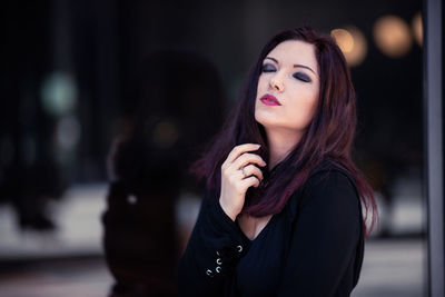 Woman standing with eyes closed against window