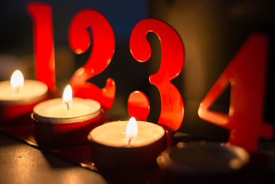 Close-up of lit tea light candles with red numbers on table