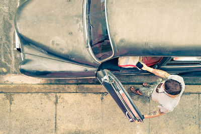 High angle view of man entering vintage car on road