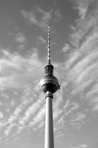 Low angle view of communications tower against cloudy sky