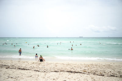 People at beach against sky