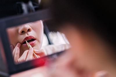 Close-up of woman applying lipstick at home