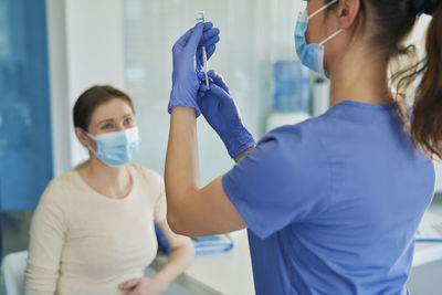 Rear view of doctor holding syringe