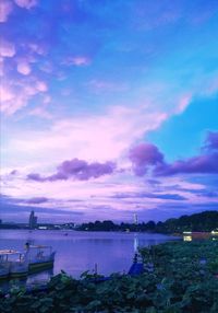 Boats moored at harbor against cloudy sky