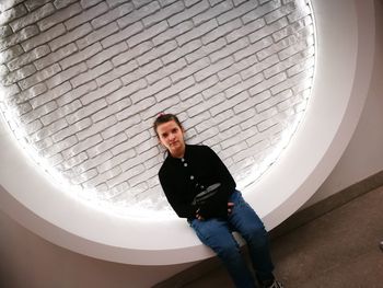 Portrait of girl sitting against illuminated wall