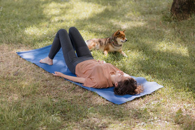 High angle view of woman lying on exercising mat at park