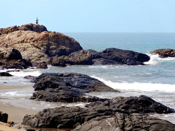 Rock formations on shore against clear sky