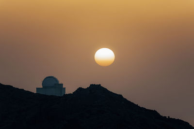 Low angle view of silhouette mountain against orange sky