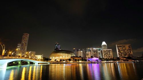 River against illuminated buildings in city at night