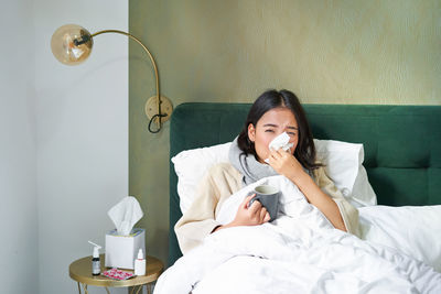 Portrait of young woman sitting on bed at home