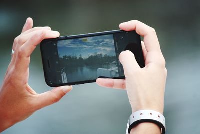 Midsection of person photographing with mobile phone