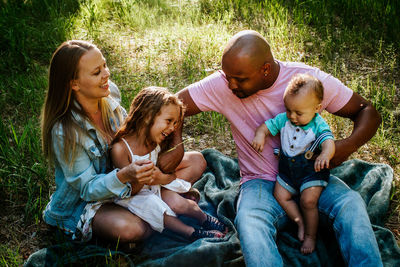 Happy young family laughing and smiling while sitting in grass