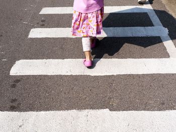 Low section of girl walking on zebra crossing