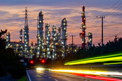 Night view of factory and car light trails at dusk.