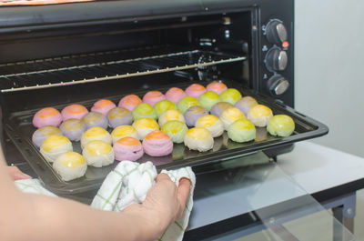 Cropped hands of man holding sweet food in baking sheet