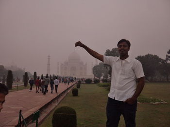 Full length of man with arms raised against sky