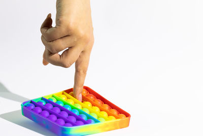 Close-up of hand holding multi colored pencils over white background