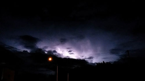 Low angle view of silhouette electricity pylon against sky at night