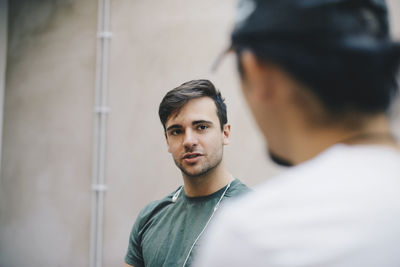 Male computer programmer talking to male colleague in office