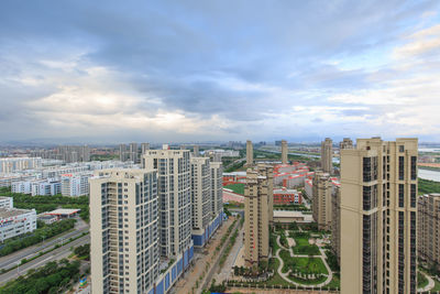 Aerial view of cityscape against cloudy sky