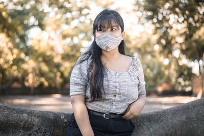 Portrait of young woman standing against tree