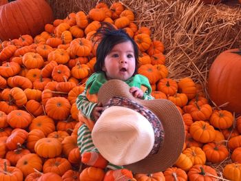 High angle view of cute baby girl sitting on pumpkins