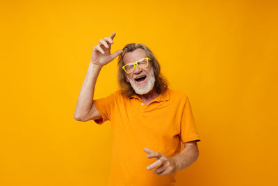 Portrait of young woman gesturing against yellow background