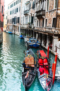 High angle view of gondolas moored in canal amidst buildings at town