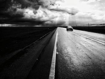 Car on road against cloudy sky