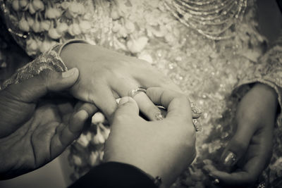 Cropped hands of man putting ring on finger