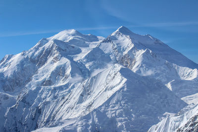 Scenic view of snowcapped mountains against blue sky