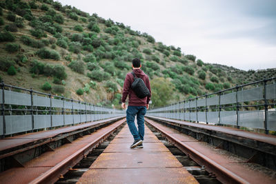 Rear view of man standing on railroad track