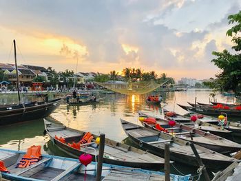 Boats moored in harbor at sunset