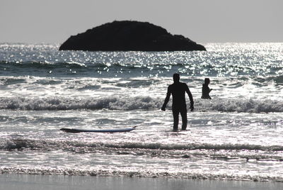 Silhouette people on beach against sky