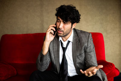 Young man using mobile phone while sitting on sofa