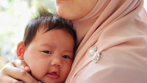 Midsection of mother embracing cute baby girl