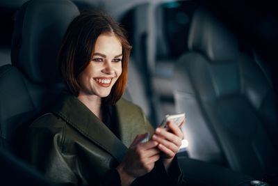 Portrait of young woman using mobile phone while sitting in car