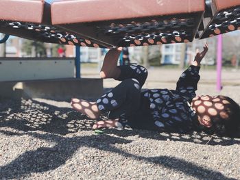 Boy lying below play equipment at playground