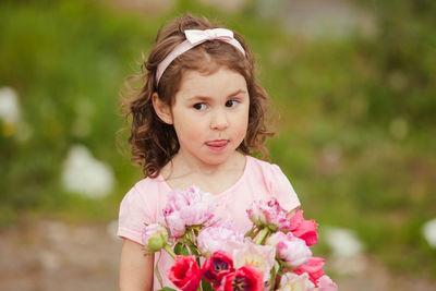 Cute girl holding tulip while standing outdoors