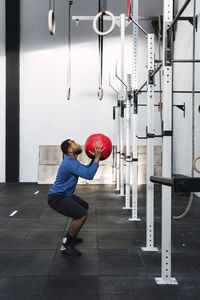 Determined athlete exercising with medicine ball in crossfit gym