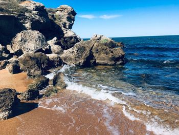 Scenic view of rocks on beach against sky