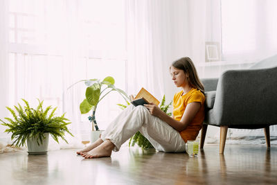 Young woman using digital tablet while sitting on sofa at home