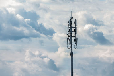 Cellular network transmitter tower on cloudy sky background, copy space