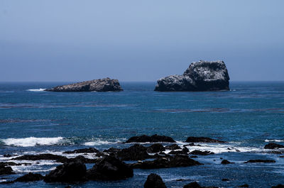 Scenic view of rocks in sea against sky