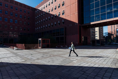 Businesswoman with laptop walking in office campus