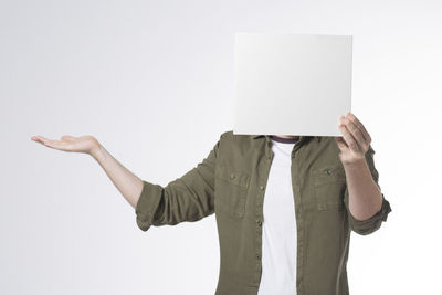 Midsection of man holding placard over face against white background