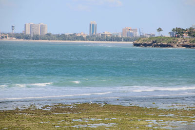 Scenic view of sea by city against sky