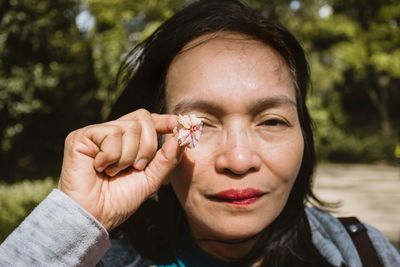 Close-up portrait of a woman with a flower in her hand