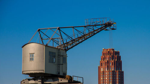 Low angle view of crane against clear blue sky