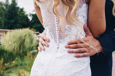 Midsection of bride embracing bridegroom during wedding ceremony